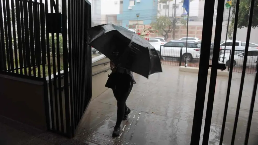 Eleitora chega para votar debaixo de chuva. (Leo de França)